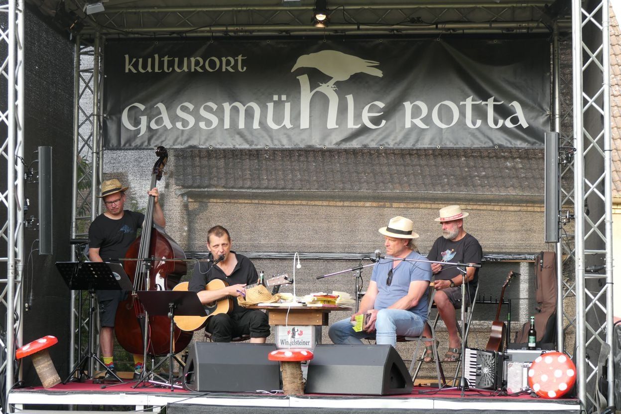 Liedertour-Festival, 26.07.2025: Schüller (Band um Ralph Schüller) akustisch auf der Open-Air-Bühne, Kontrabass, Akkordeon, Banner „Kulturort Gassmühle Rotta“, Abendlicht